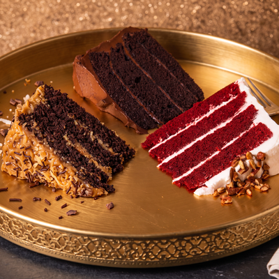 German chocolate, dark chocolate and red velvet cake slices on a gold tray